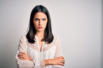 Young brunette woman with blue eyes wearing casual t-shirt over isolated white background skeptic and nervous, disapproving expression on face with crossed arms. Negative person.