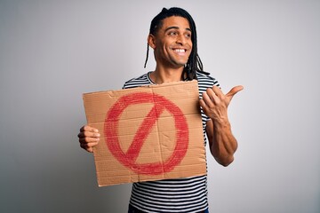 Wall Mural - Young handsome african american man with dreadlocks holding banner with prohibited signal pointing and showing with thumb up to the side with happy face smiling