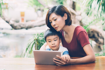 Wall Mural - Son using digital tablet computer for study and learn to internet online with mother together, education from home, family recreation, mom teach boy with technology media, lifestyle concept.