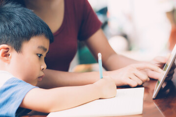 Wall Mural - Son using digital tablet computer for study and learn to internet online with mother together, education from home, family recreation, mom teach boy and homework with technology, lifestyle concept.