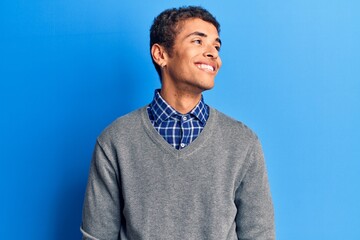 Young african amercian man wearing casual clothes looking away to side with smile on face, natural expression. laughing confident.