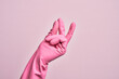 Hand of caucasian young man with cleaning glove over isolated pink background snapping fingers for success, easy and click symbol gesture with hand
