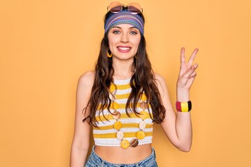 Wall Mural - Young beautiful hippie woman with blue eyes wearing accesories and sunnglasses smiling looking to the camera showing fingers doing victory sign. Number two.