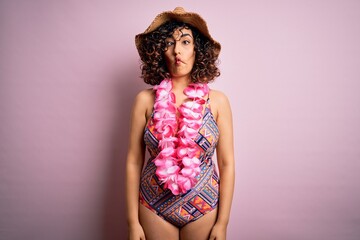 Poster - Young beautiful arab woman on vacation wearing swimsuit and hawaiian lei flowers making fish face with lips, crazy and comical gesture. Funny expression.