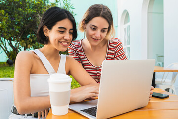 Two young friends using a laptop at coffee shop.