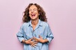 Leinwandbild Motiv Middle age beautiful woman wearing casual denim shirt standing over pink background smiling and laughing hard out loud because funny crazy joke with hands on body.