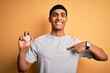 Young handsome african american man doing sport using stopwatch over yellow background with surprise face pointing finger to himself