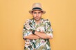 © Krakenimages.com - Young handsome man with blue eyes on vacation wearing summer florar shirt and hat skeptic and nervous, disapproving expression on face with crossed arms. Negative person.
