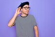 © Krakenimages.com - Handsome man with blue eyes wearing striped t-shirt and french beret over purple background smiling with hand over ear listening an hearing to rumor or gossip. Deafness concept.