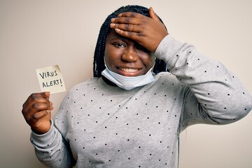 Poster - African american woman wearing medical mask holding reminder with virus alert message stressed with hand on head, shocked with shame and surprise face, angry and frustrated. Fear and upset