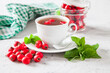 tea with a hawthorn and mint in a cup on a table, selective focus