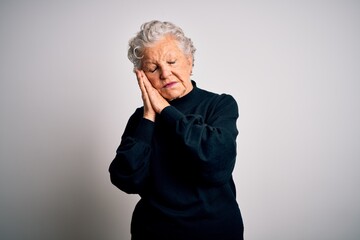 Wall Mural - Senior beautiful woman wearing casual black sweater standing over isolated white background sleeping tired dreaming and posing with hands together while smiling with closed eyes.