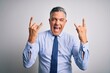 © Krakenimages.com - Middle age handsome grey-haired business man wearing elegant shirt and tie shouting with crazy expression doing rock symbol with hands up. Music star. Heavy music concept.