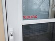 red no soliciting sign on glass of screen door