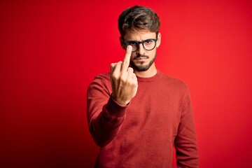 Poster - Young handsome man with beard wearing glasses and sweater standing over red background Showing middle finger, impolite and rude fuck off expression