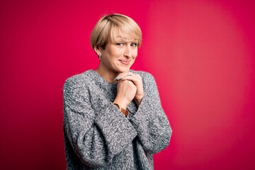 Poster - Young blonde woman with modern short hair wearing casual sweater over pink background laughing nervous and excited with hands on chin looking to the side