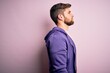 © Krakenimages.com - Young blond man with beard and blue eyes wearing purple sweatshirt over pink background looking to side, relax profile pose with natural face with confident smile.