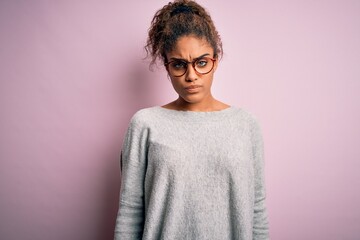 Canvas Print - Young beautiful african american girl wearing sweater and glasses over pink background skeptic and nervous, frowning upset because of problem. Negative person.