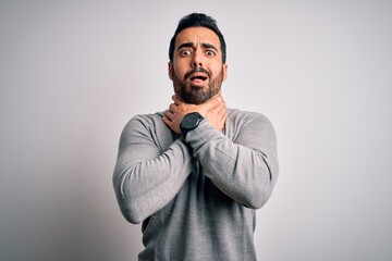 Sticker - Young handsome man with beard wearing casual sweater standing over white background shouting and suffocate because painful strangle. Health problem. Asphyxiate and suicide concept.