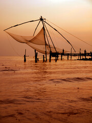 Wall Mural - silhouette of fisherman fishing with large net during sunset in cochin - india 