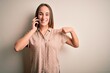 © Krakenimages.com - Young beautiful woman having conversation talking on the smartphone over white background looking confident with smile on face, pointing oneself with fingers proud and happy.