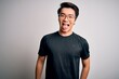 © Krakenimages.com - Young handsome chinese man wearing black t-shirt and glasses over white background sticking tongue out happy with funny expression. Emotion concept.