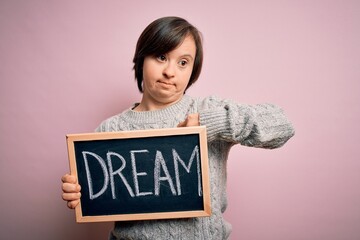 Sticker - Young down syndrome woman holding blackboard with dream word as message of happiness with surprise face pointing finger to himself