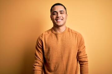 Wall Mural - Young brazilian man wearing casual sweater standing over isolated yellow background with a happy and cool smile on face. Lucky person.