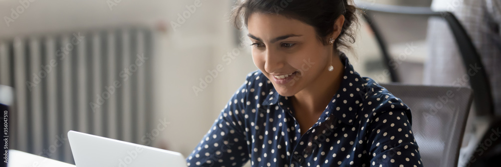 Young woman Indian employee sit at desk in office room use computer do work. Workday, human resources, career, new app corporate program usage concept horizontal photo banner for website header design - obrazy, fototapety, plakaty 