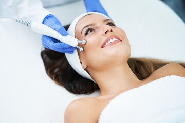 Poster - Beautiful young woman getting face treatment at beauty salon.