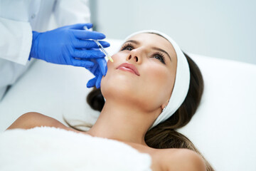 Beautiful young woman getting acid face treatment at beauty salon.