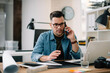 © JustLife - Businessman in office. Handsome man talking on phone at work.