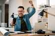 © JustLife - Happy businessman using laptop in his office. Young businessman working.