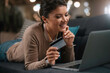 © JustLife - Young businesswoman at home makes a purchase on the Internet. Beautiiful woman on the laptop with credit card