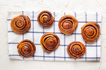 Wall Mural - baked cinnamon buns on light background with checkered napkin