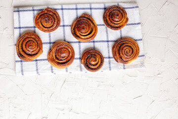 Wall Mural - baked cinnamon buns on light background with checkered napkin