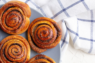 Wall Mural - baked cinnamon buns on grey plate on light background with checkered napkin
