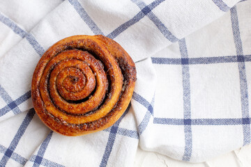 Wall Mural - baked cinnamon buns on light background with checkered napkin