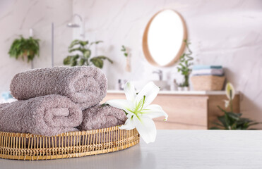 Wall Mural - Fresh towels and lily flower on wooden table in bathroom. Space for text