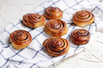 Wall Mural - baked cinnamon buns on light background with checkered napkin
