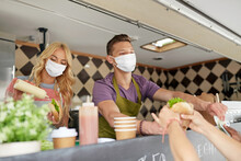 Street Sale And People Concept - Young Sellers Wearing Face Protective Medical Mask For Protection From Virus Disease Serving Customers At Food Truck