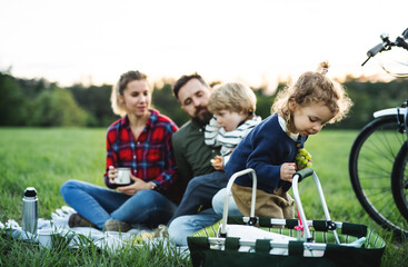 Wall Mural - family with two small children on cycling trip, sitting on grass and resting.