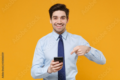 Fotomural Smiling young business man in classic blue shirt tie posing isolated on yellow background studio