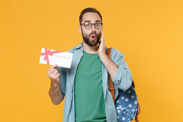 Wall Mural - Shocked man student in casual clothes glasses backpack isolated on yellow background. Education in high school university college concept. Mock up copy space. Hold gift certificate, put hand on cheek.