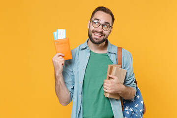 Poster - Pensive young man student in casual clothes glasses backpack hold books passport boarding pass tickets isolated on yellow background. Education in university college abroad. Air travel flight concept.