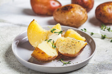 Canvas Print - Baked potatoes with butter and thyme on gray plate.