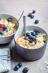 Oatmeal bowl with banana, berries, hemp seeds and coconut slices. Healthy vegan breakfast concept.