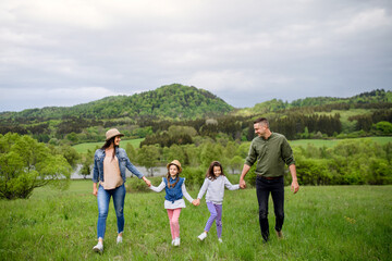 Happy family with two small daughters walking outdoors in spring nature.