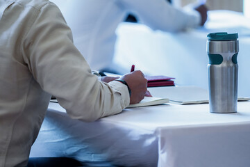 close up to seminar audience with their glass and gadget on the table.