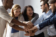 © fizkes - Close up image overjoyed 5 multi ethnic business people stack touch arms palms together celebrating promotion reward, succeed common aim. Give high five symbol of unity, team building activity concept